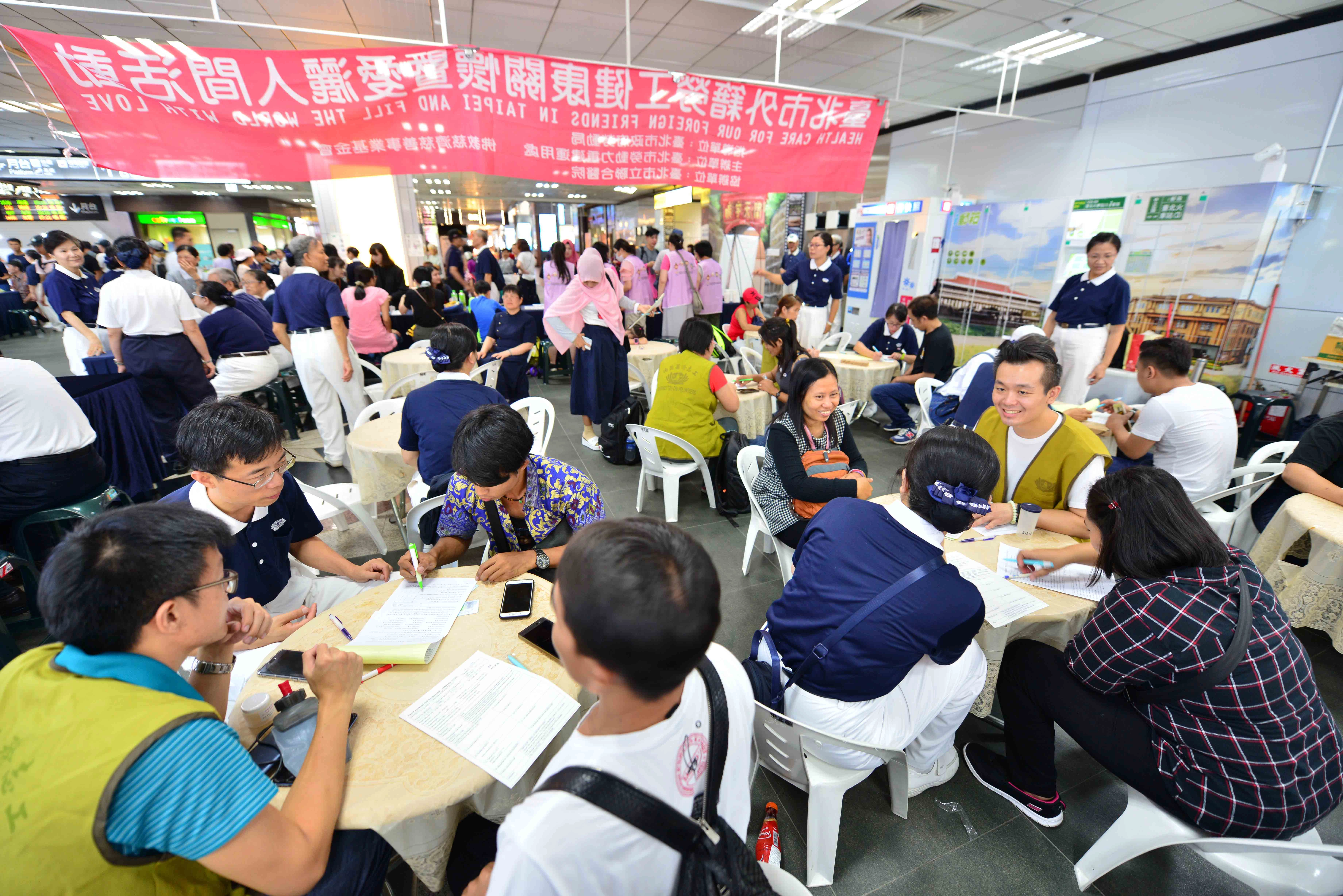填表區裡,翻譯志工熱絡地和移工們互動並協助填表動作。