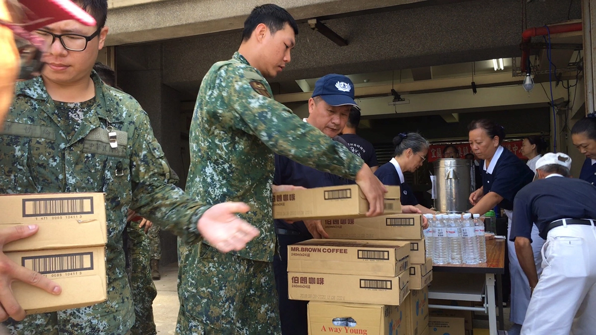慈濟志工進駐「南方澳大橋斷橋事故」現場成立服務中心,國軍協助慈濟志工搬運物資。