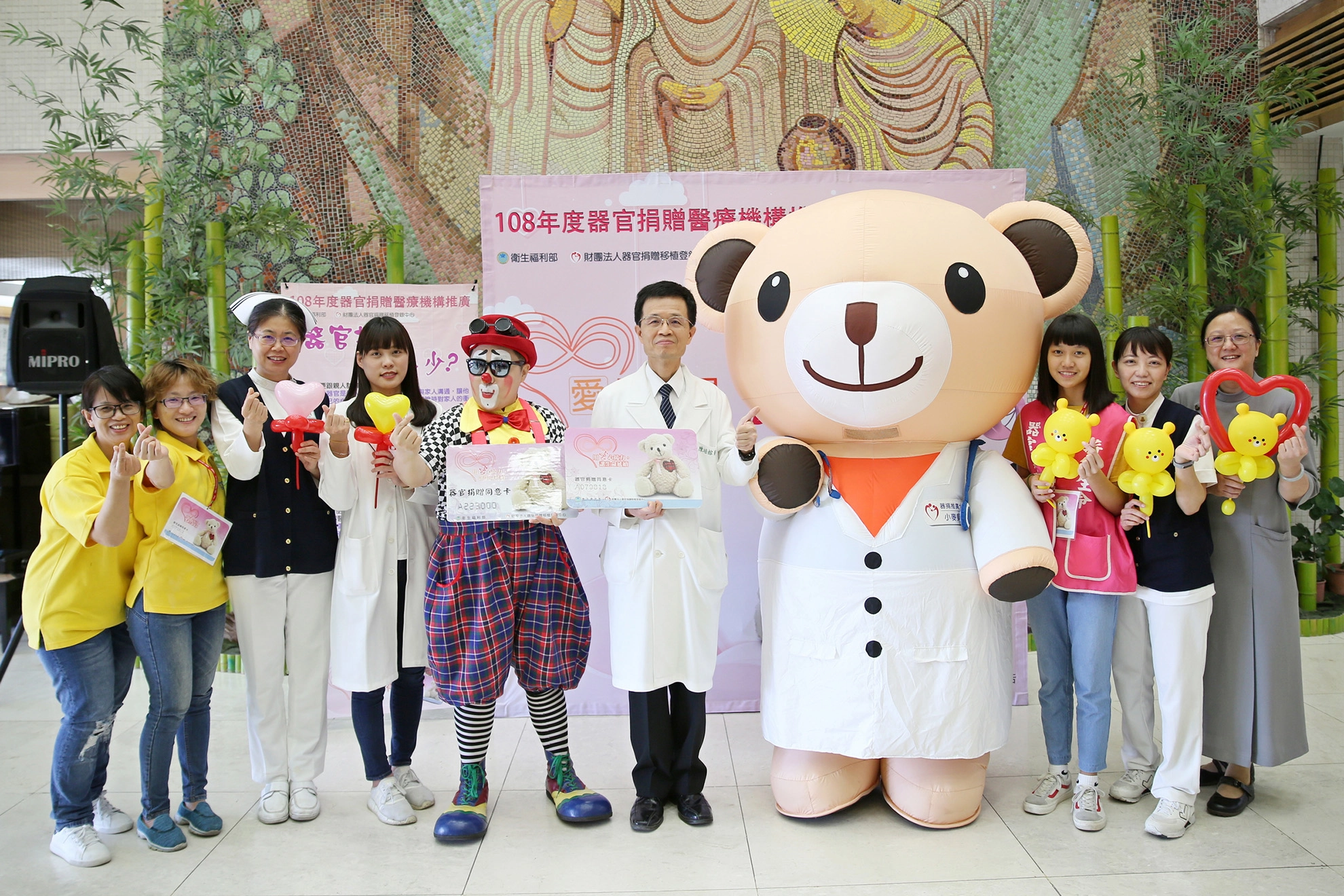 花蓮慈濟醫院副院長陳培榕(右五)與小麥貝兒熊(右四)、小丑熊熊(左五)及器捐宣導團隊邀約民眾一起來簽署器官捐贈同意書。