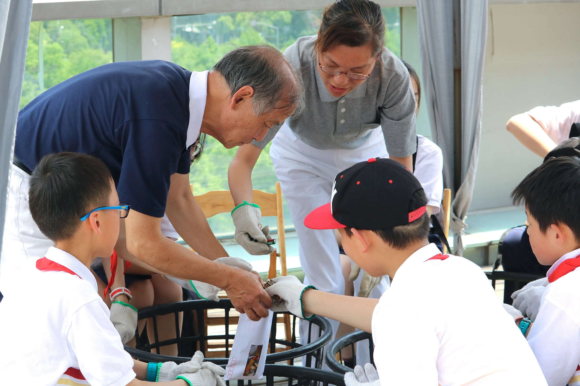 慈濟志工帶動學生一起分類資源回收物,把電池放在一起,透過環保實作,學習資源回收分類。