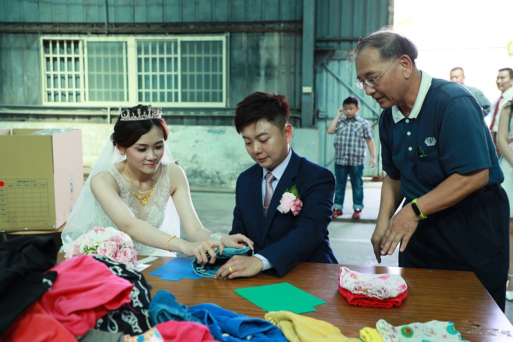 張毓哲與新婚的妻子卓雨親一起摺同一件衣服,整理募集的衣物,送到莫三比克給當地的孩童。