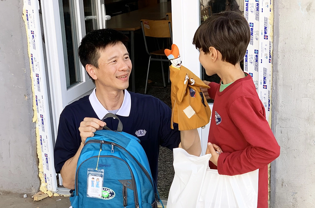 歐洲慈濟志工長期關心滯留在塞爾維亞的各國難民;慈濟志工發放新書包和文具用品給難民孩子。林正中師兄(左)用布袋戲與小朋友互動。