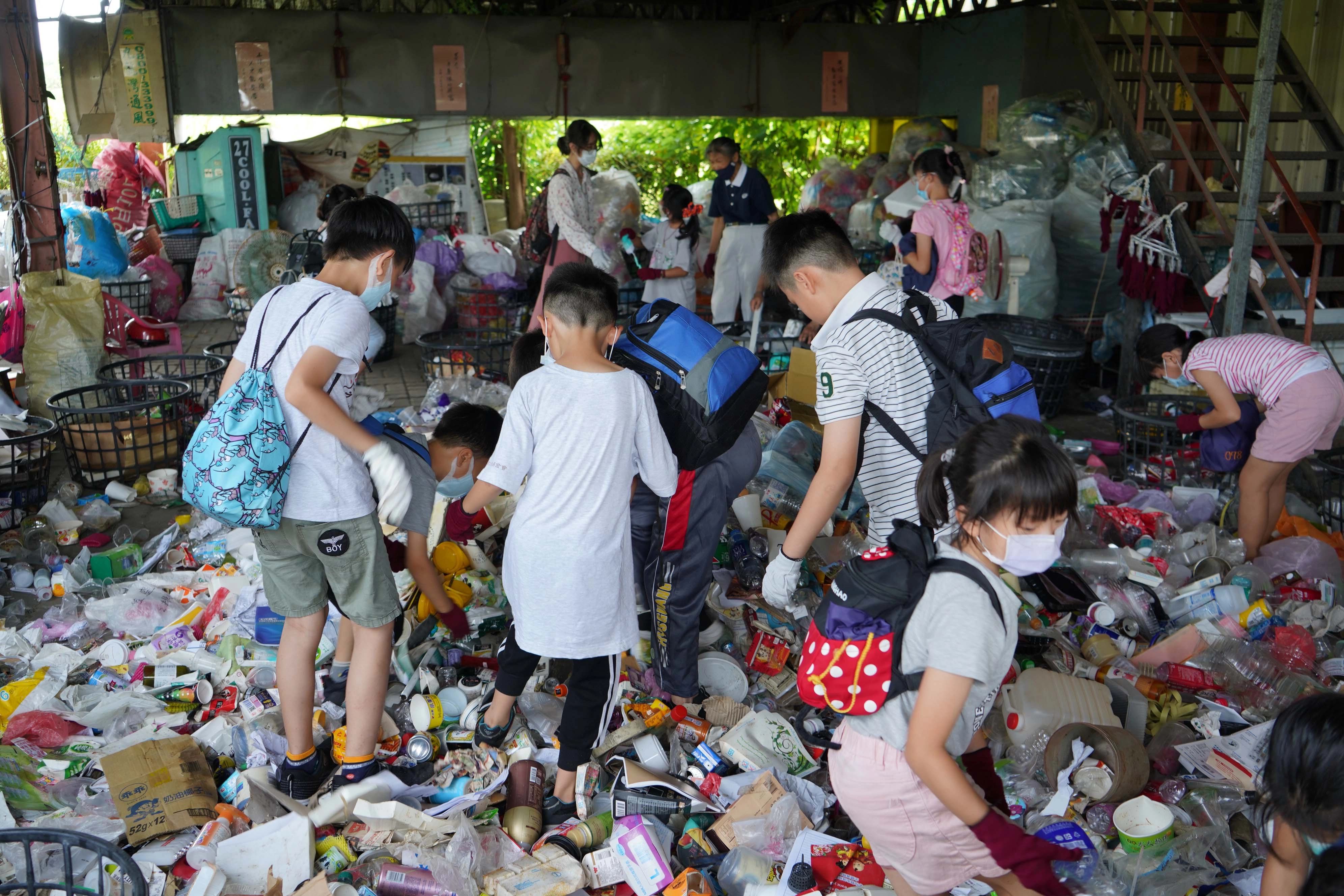 離開了有冷氣的教室,「資源分類體驗」分為四組,來到環保站內的實作區進行實作,然而暑熱的高溫天氣,還沒動手做,已讓大家額頭開始冒汗了!活潑好動的孩子們卻顯得興致勃勃,有人踩寶特瓶、也有人進行分類。
