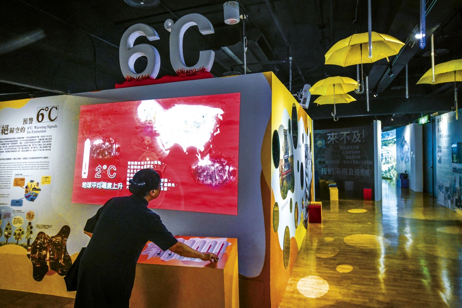 高雄靜思堂環境教育館內,負責解說的志工操作按鈕,螢幕即顯示地球暖化每升高一度所遭遇的狀況。