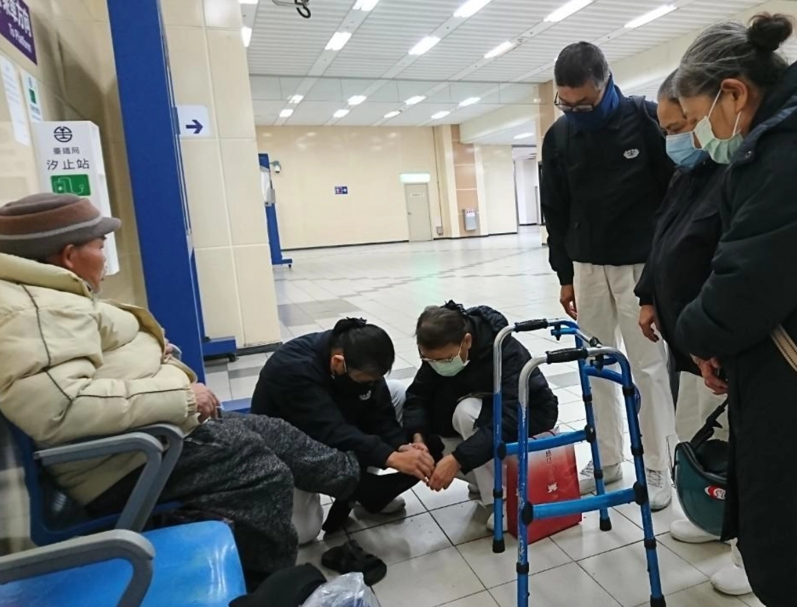 汐止慈濟志工前往汐止車站關懷街友,親自為他們穿上防寒衣物襪。