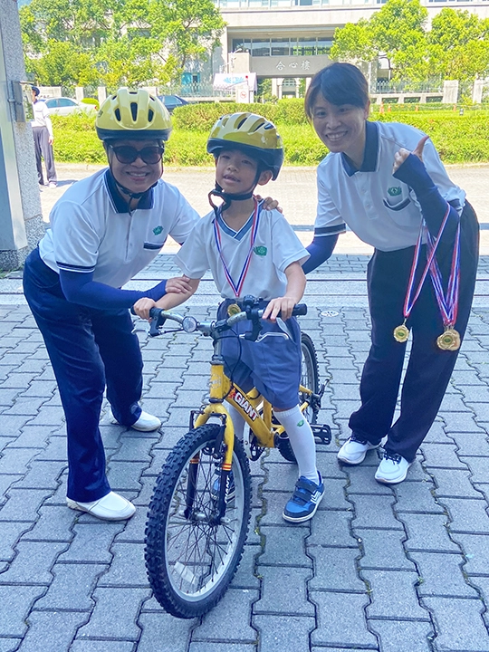 完賽後幼兒從園長陳佩珠手中領取完賽證明獎牌,象徵挑戰成功,順利畢業。