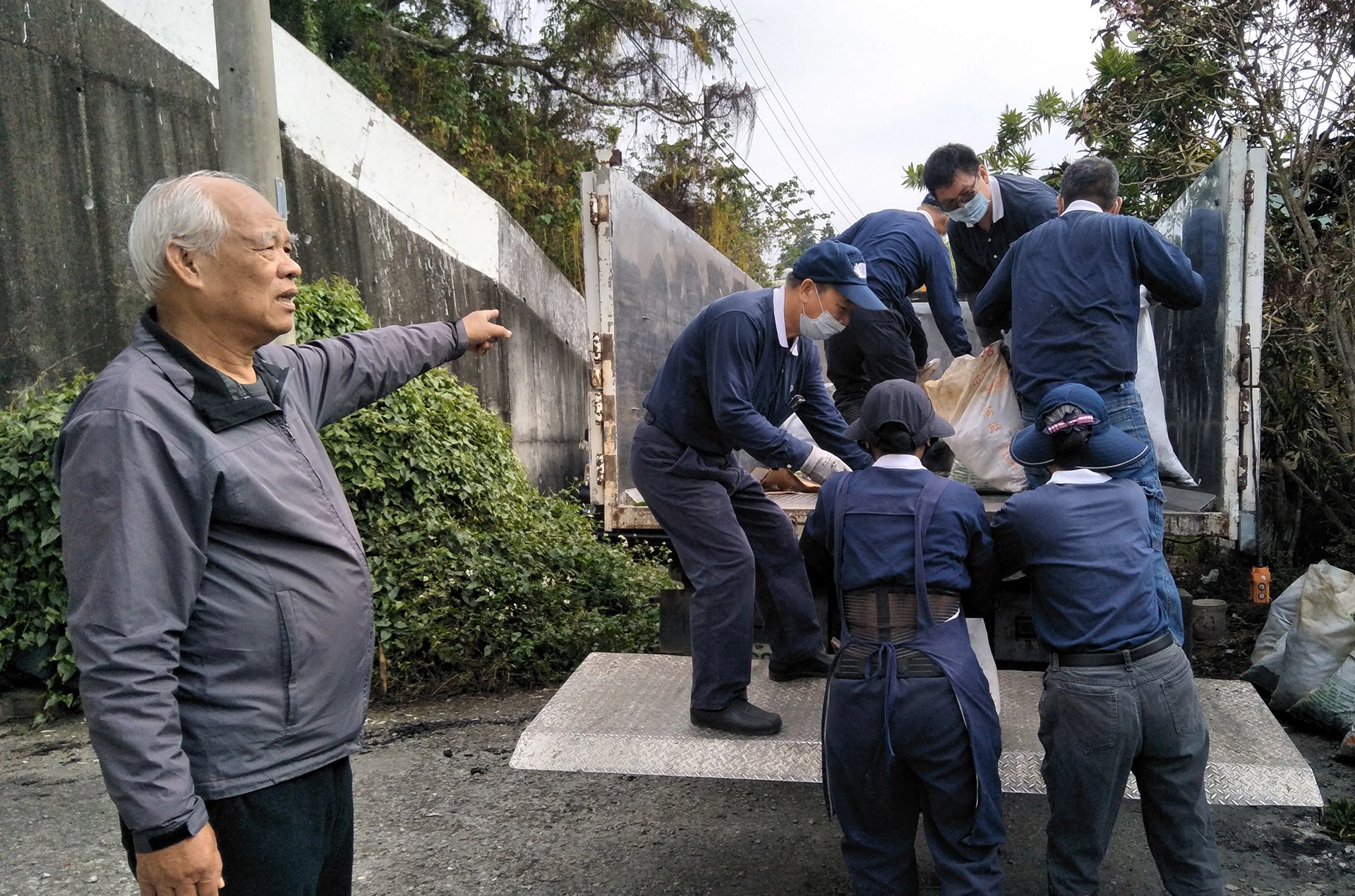 草屯鎮公所清潔隊協助載運清理出來的廢棄物,洪智捷里長(左)親臨現場關懷,里長夫人也協助清掃。