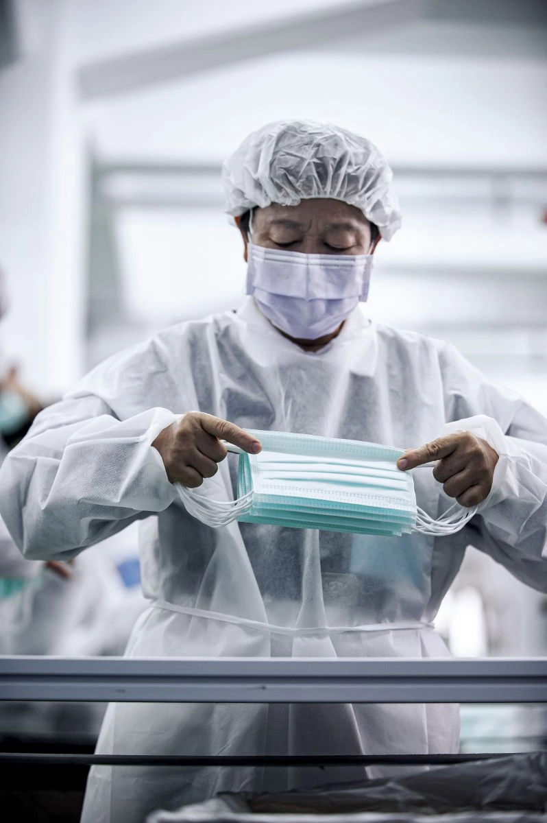 依據口罩工廠廠方人員指導,志工清潔消毒雙手、穿上無塵衣,專注整理口罩。