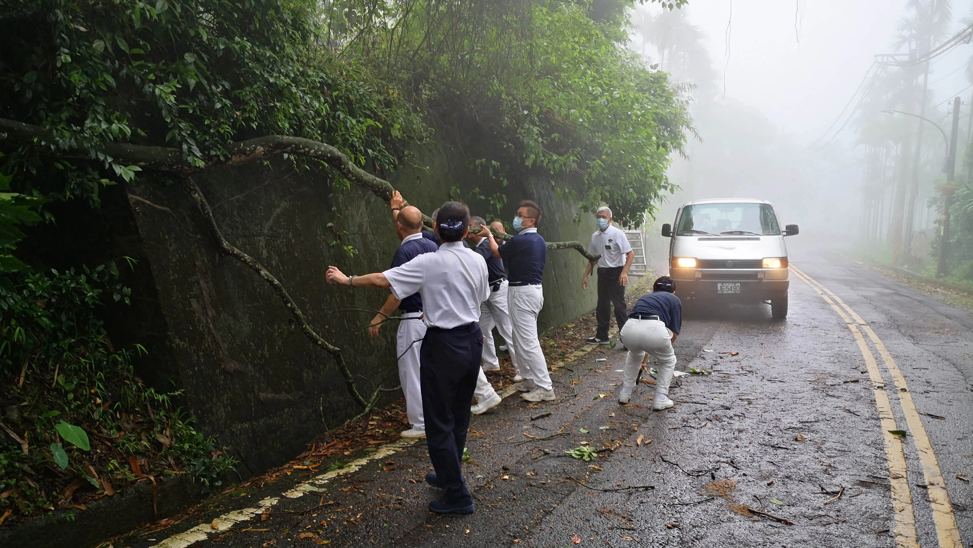 志工前往樟湖村往診途中，被從山上滑落的樹擋住去路，志工下車合力移動，繼續往前。