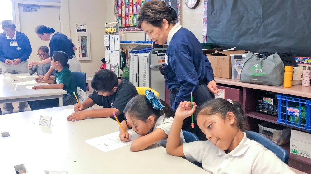 二○一九年加州聖塔安那市麥迪遜小學「幸福校園背包計畫」,透過活動為孩子們進行近距離的引導,聆聽孩子的心聲。呂美力巡著孩子們的學習單。圖/林綺芬提供