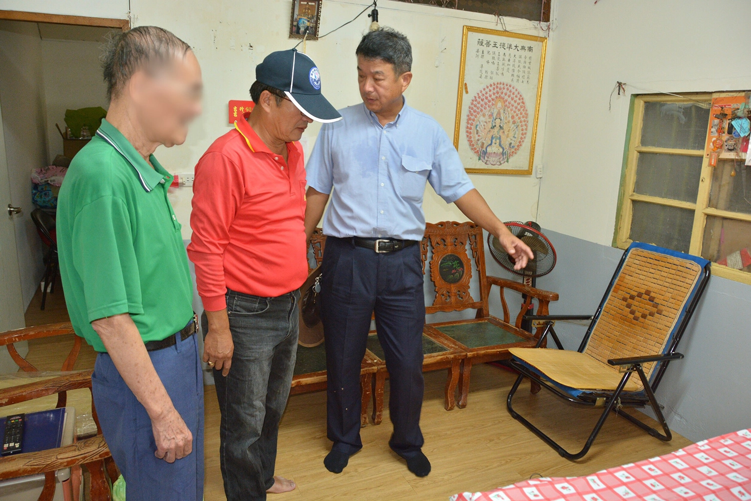 慈濟營建處陳文亮(右)向里長謝銀樹(中)介紹修繕區域,圖為客廳,已舖上新地板、重新粉刷。