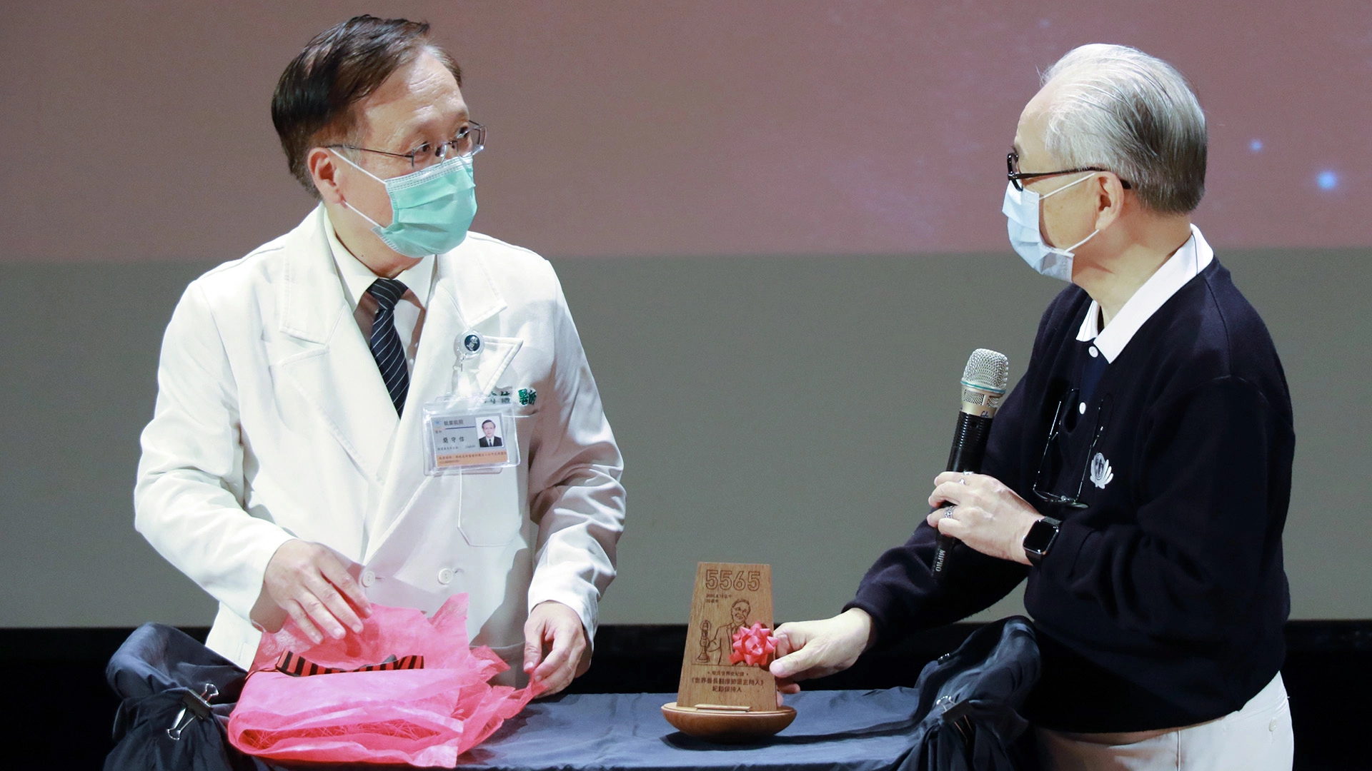 慈濟傳播人文志業基金會合心精進長姚仁祿(右)頒發親自設計的「世界最長醫療節目主持人紀錄保持人」獎項給簡守信。