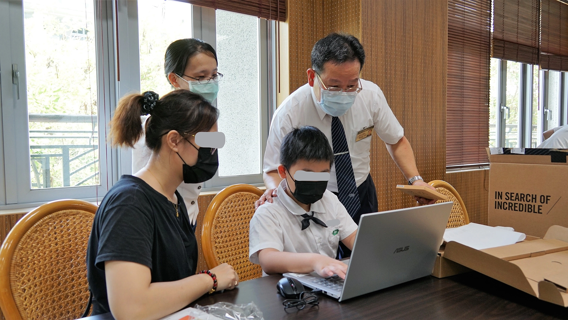 國小部學生家長與教務主任陪同學生操作筆電。許翠卿 攝