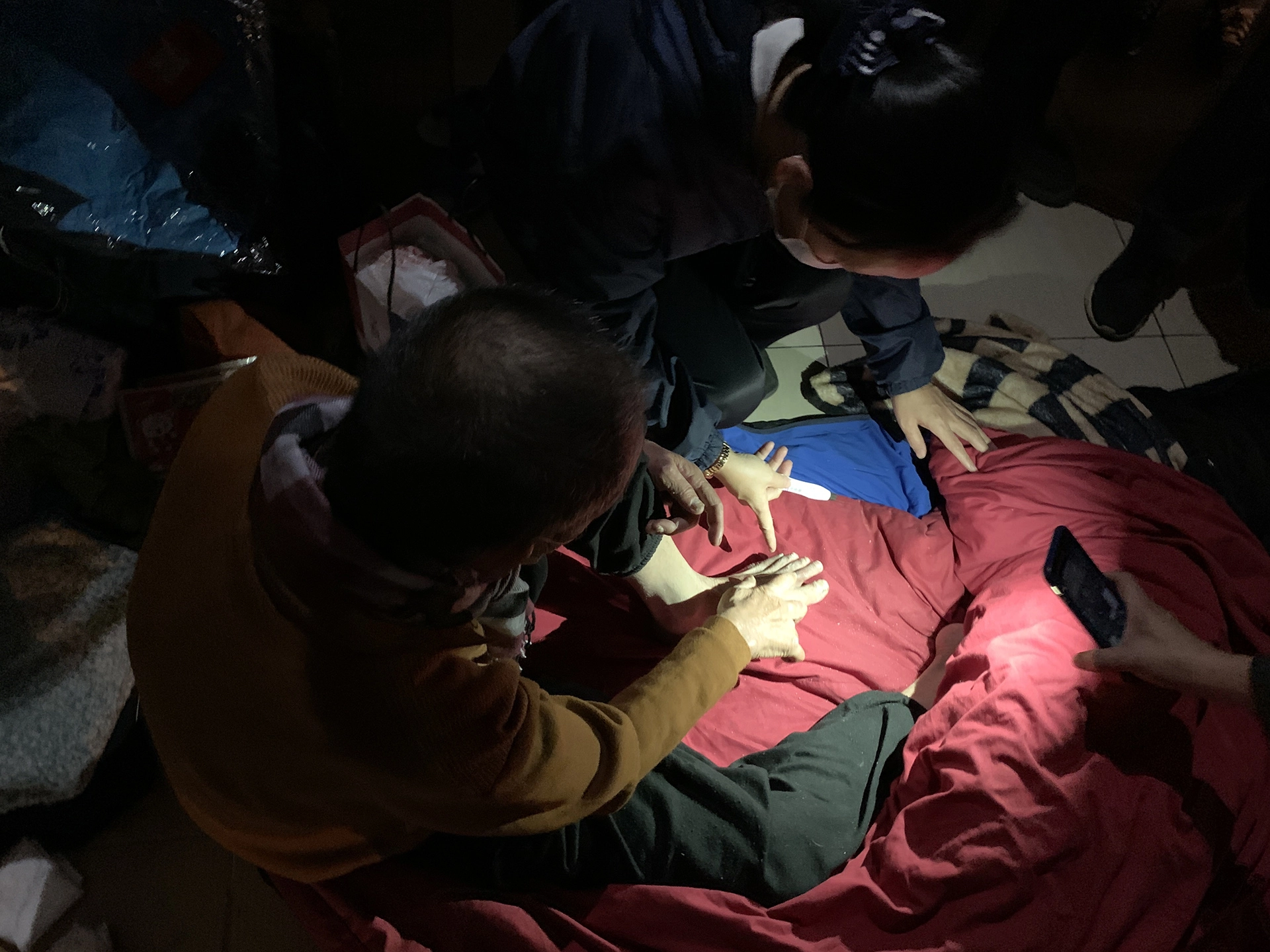 騎樓下必須依賴手機燈光的照射,人醫會的醫護人員才能清楚看到街友腳上凍裂的傷口。