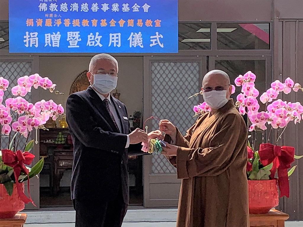 2月24日雲林慈濟志工余天助(左)代表致贈組合教室鑰匙,由印可法師(右)代表領取。