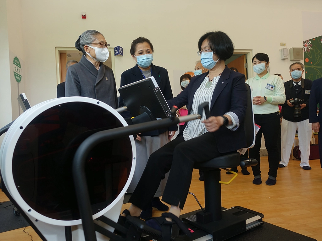 彰化縣長王惠美在慈濟長照總召集人林碧玉(左一)、副召集人莊淑婷(左二)陪伴下,體驗日照中心長者的健身器材。