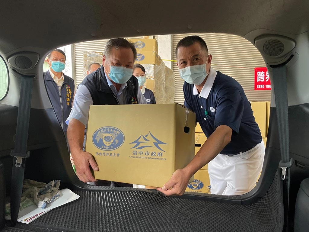 農業局蔡精強局長(左)與志工吳欽堂(右)將物資搬上計程車,蔡精強表示這樣的跨界合作非常有意義。(攝影:台中市政府)