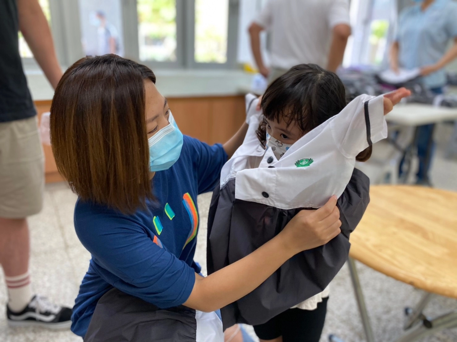 幼兒園新生在家長與老師的協助下,第一次試穿制服,準備迎接人生新階段。攝影:臺南