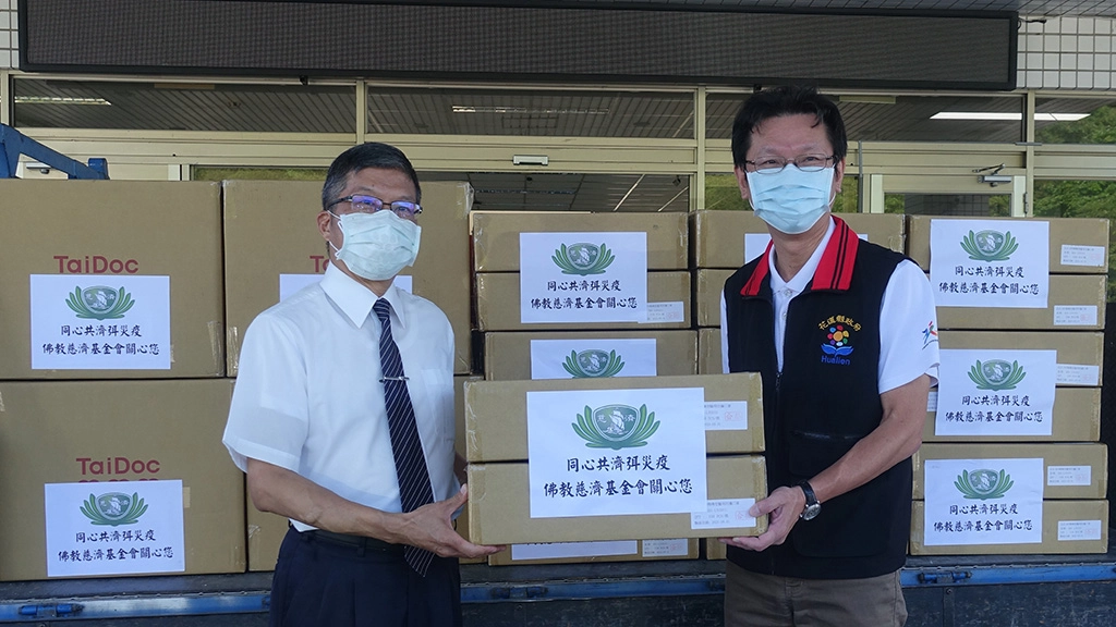 慈濟6月12日提供花蓮縣衛生局快篩試劑、N95口罩各5千個,由副執行長劉效成(左)致贈給衛生局長朱家祥(右)。