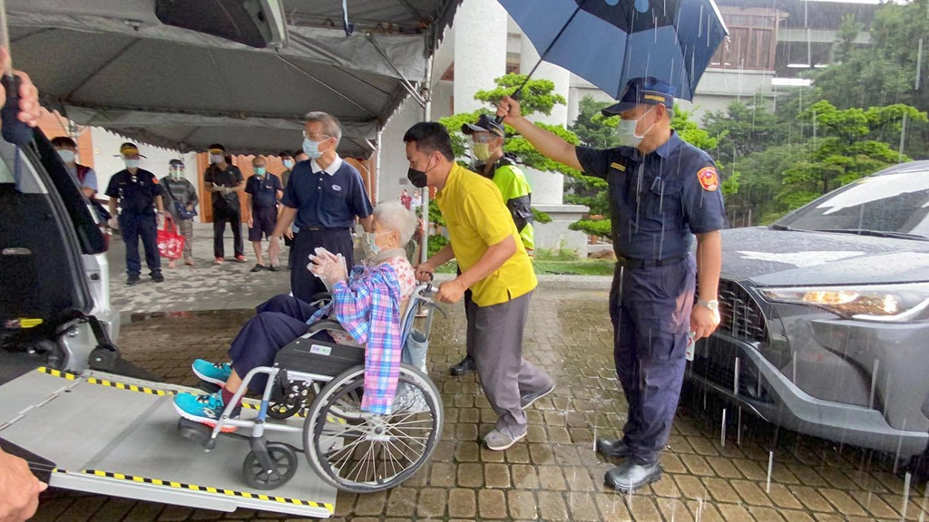 高雄三民二分局長黃文哲，一早就到高雄靜思堂關心施打民眾進出安全並在雨中為民眾撐傘。