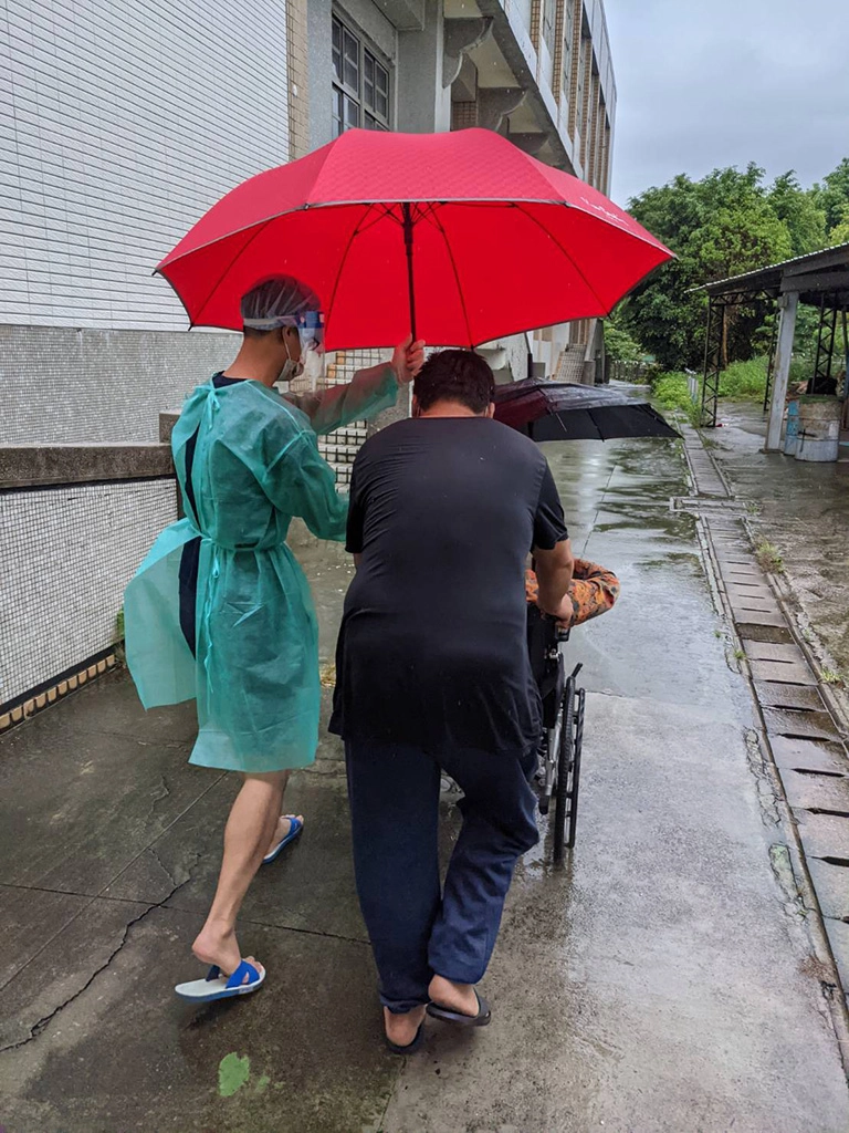 豐原區快打站工作人員協助撐傘,避免接種疫苗長輩被雨淋濕。