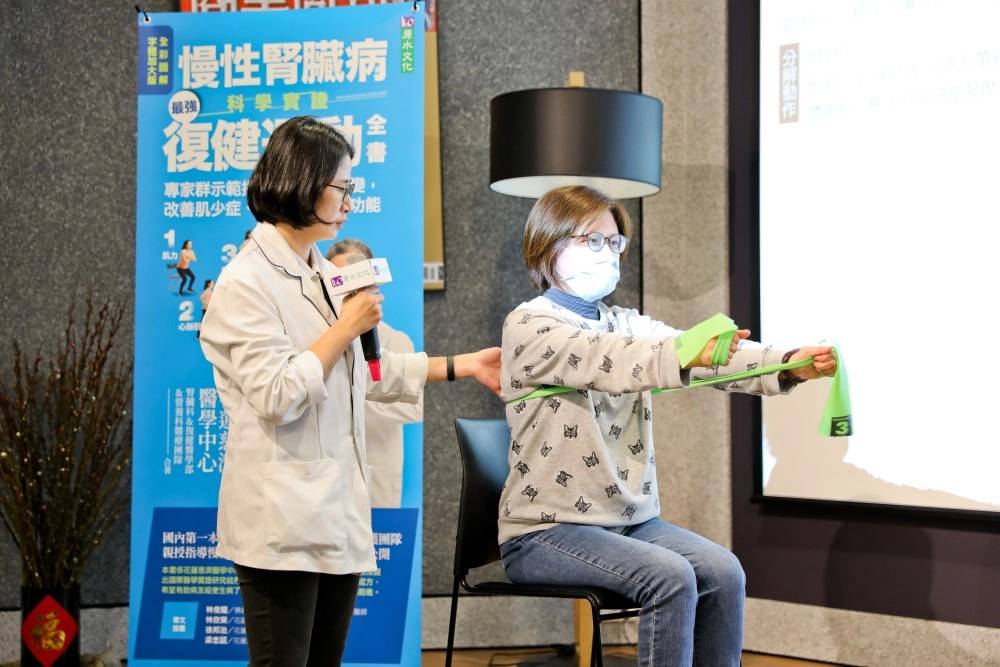 復健醫學部物理治療師黃意雯教導腎友坐著也能強化手及腳部肌力的簡單方法,示範者為張逸真個案管理師。