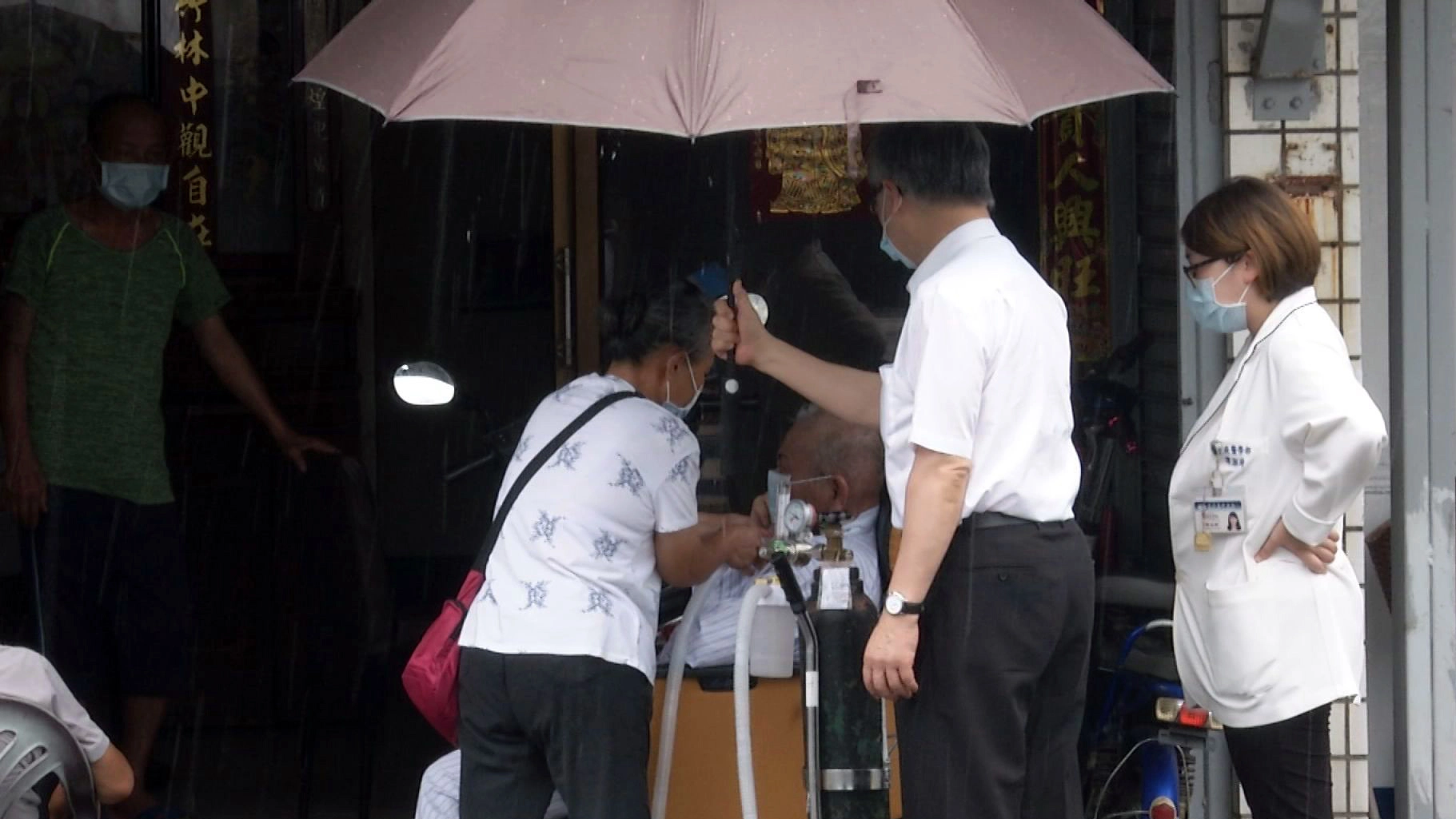突然下起雨,捨不得打斷吳先生與家人在門前對坐的時刻,王英偉主任為吳先生撐傘,並隨時注意吳先生的身體狀況。