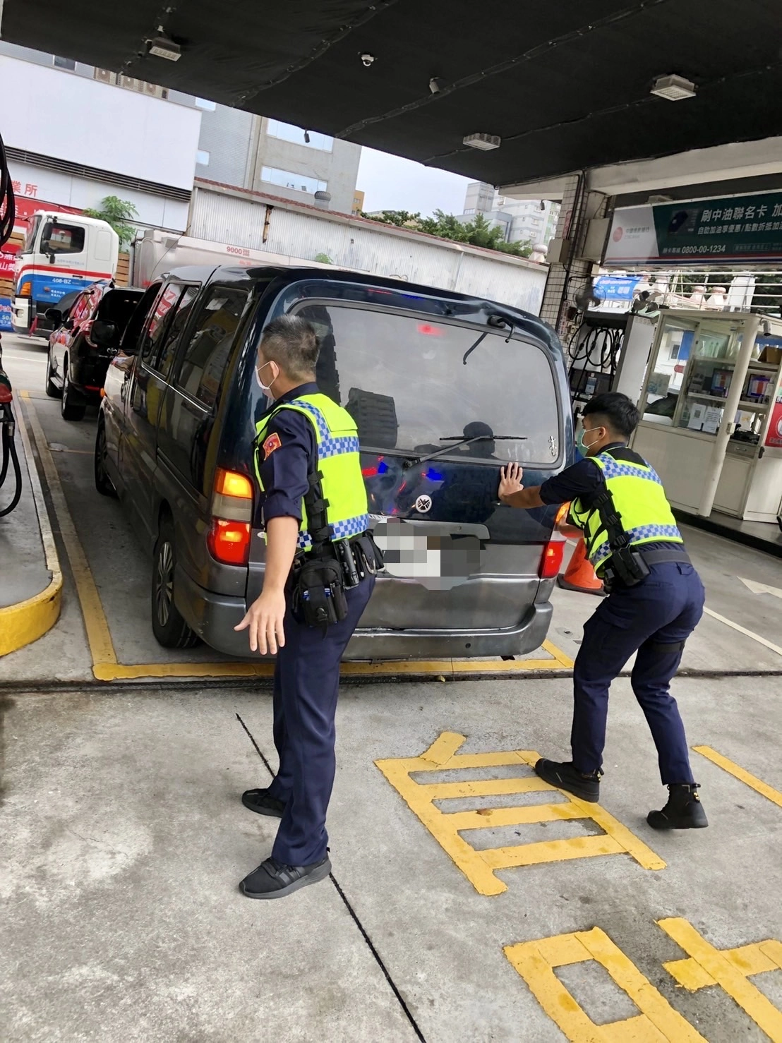 保安大隊小隊長洪輝武與警員蘇煜斌合力,終於將箱型貨車推上加油站的斜坡,順利進入加油島進行加油。