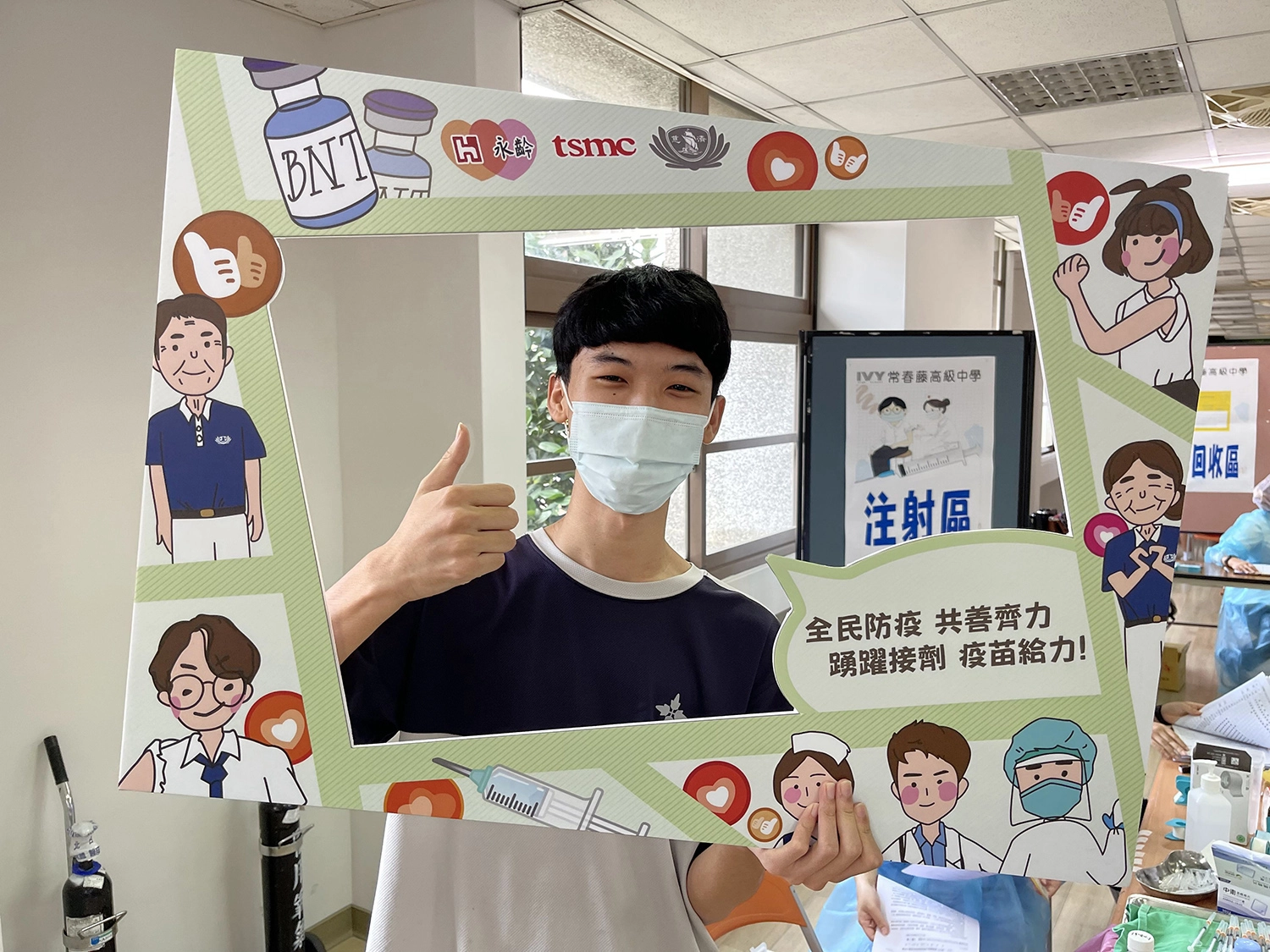 同學打完疫苗,開心拿打卡板比讚拍照留念。