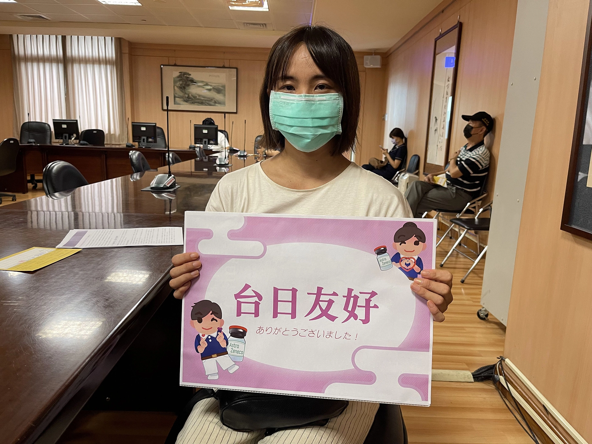 疫苗接種結束,保田女士在休息區手持「台日友好」手板留影。