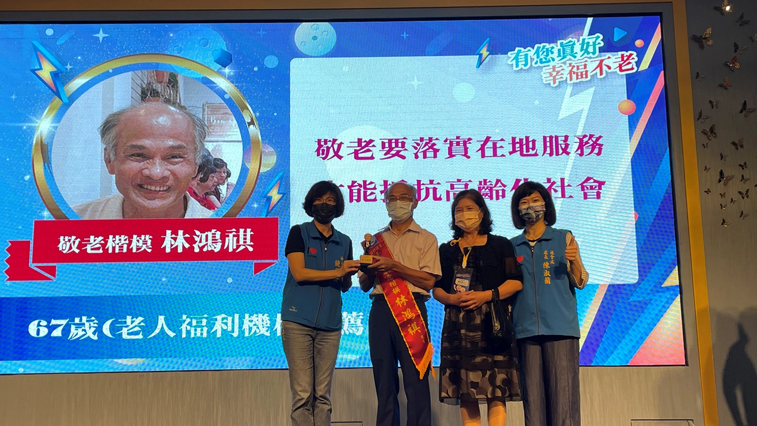 台東慈濟志工林鴻祺(左二)獲得2021年台東縣敬老楷模獎,由縣長饒慶鈴(左一)頒獎,太太陳素敏(右二)陪同。(攝影:羅庭茜)
