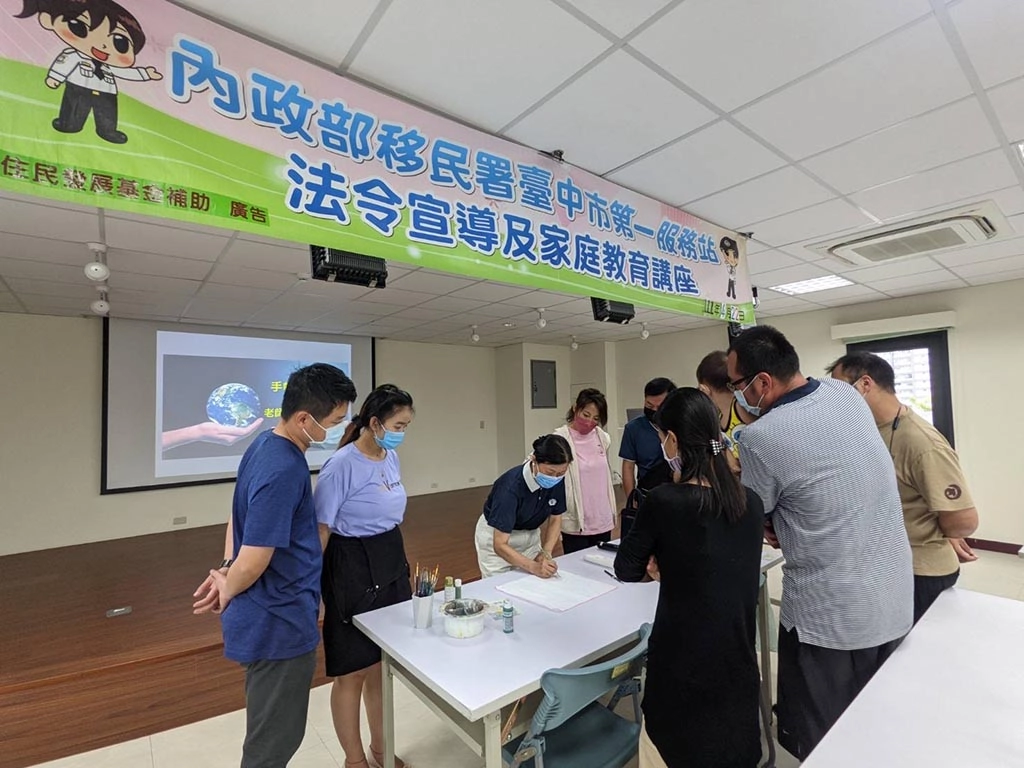 世界地球日移民署響應環保從日常做起,家庭教育活動師姐示範彩繪手帕。