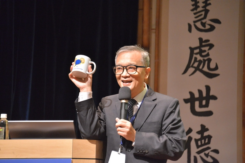 台北慈濟醫院楊緒棣副院長展示研討會紀念品,並以「甘願做,歡喜受」表達慈濟的人文精神。