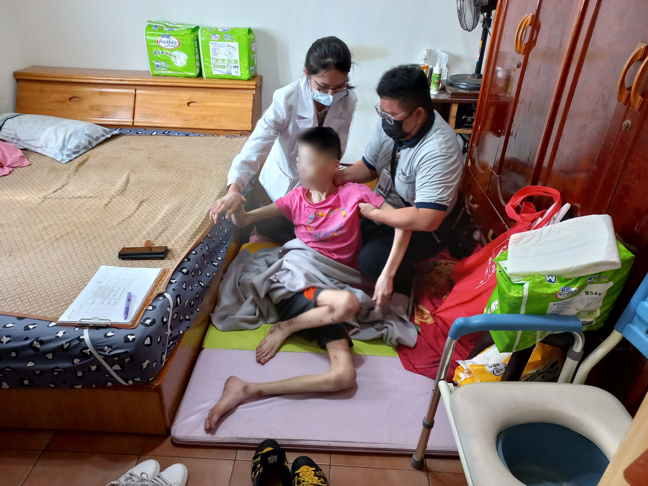 莊孟臻醫師(後)評估病人身體,建議用鼻胃管灌食,改善病人嗆咳問題。