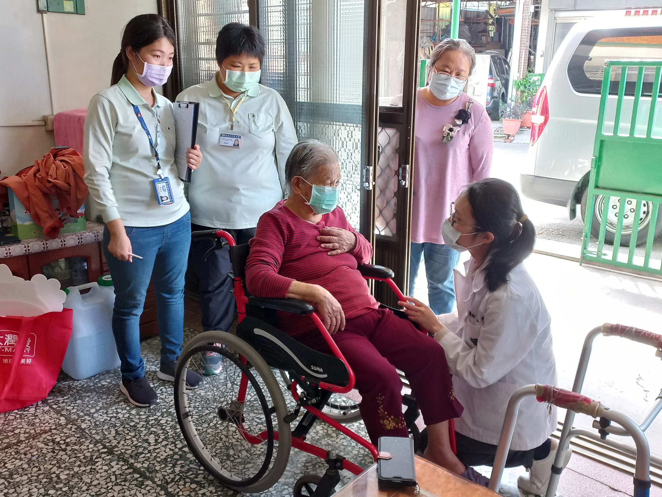 莊孟臻醫師(右)蹲下關心往診長者健康。