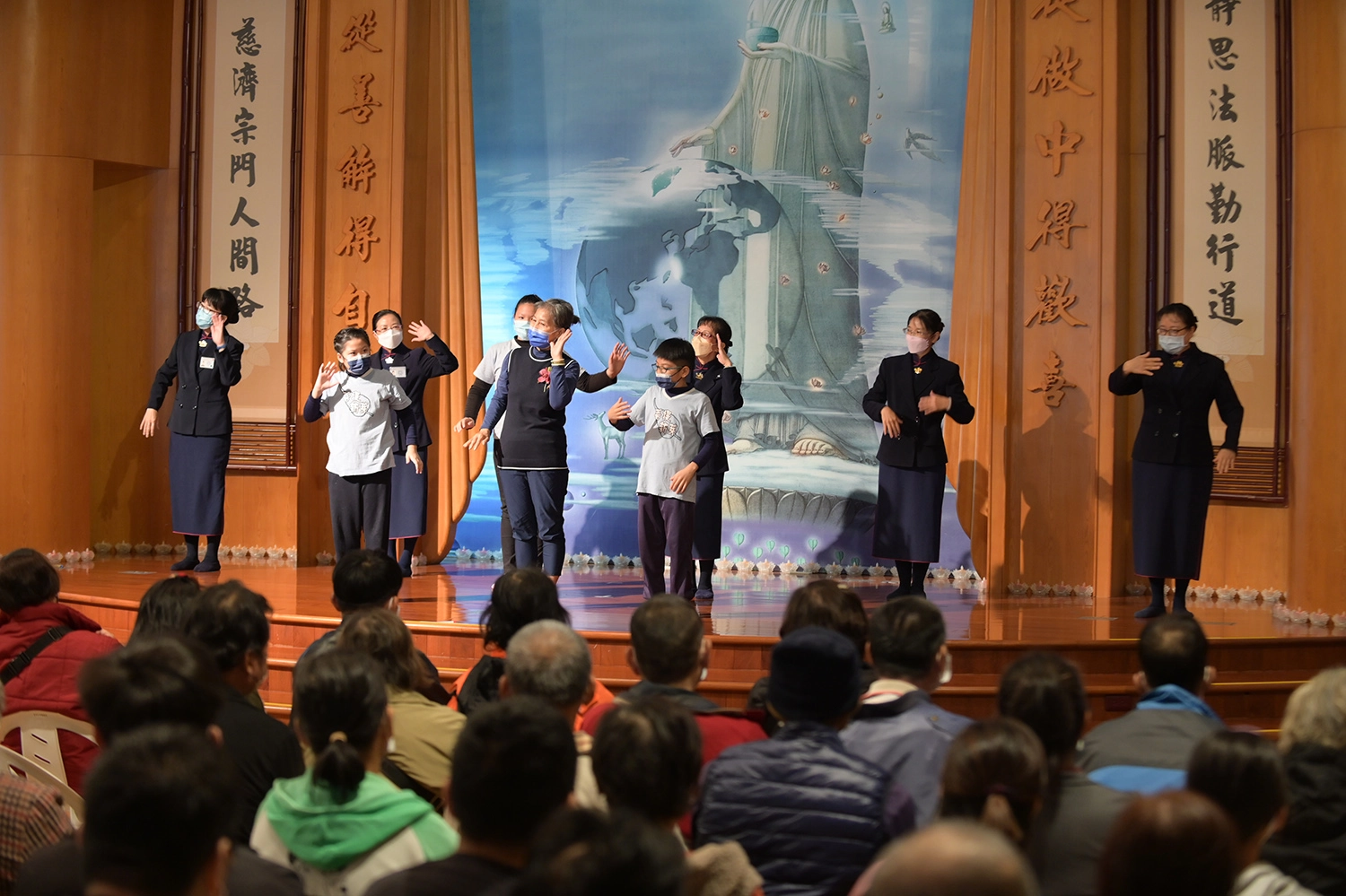 台東慈濟12月31日舉辦冬令發放活動,照顧戶侯女士與孫子上台表演手語。(攝影:陳信安)