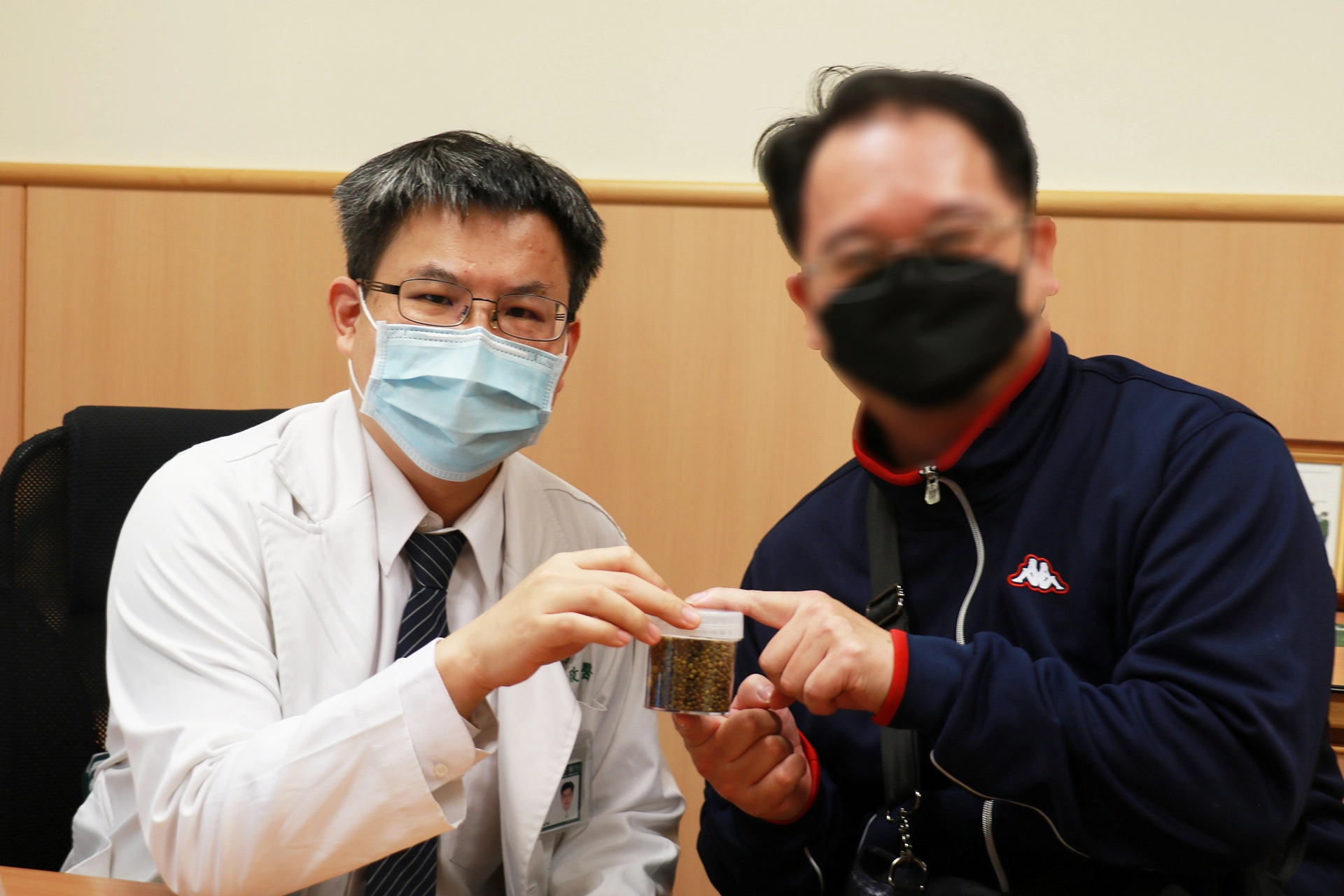 余政展主任(左)拿著膽囊取出的一整瓶膽結石,叮嚀回診病人清淡飲食保健康。