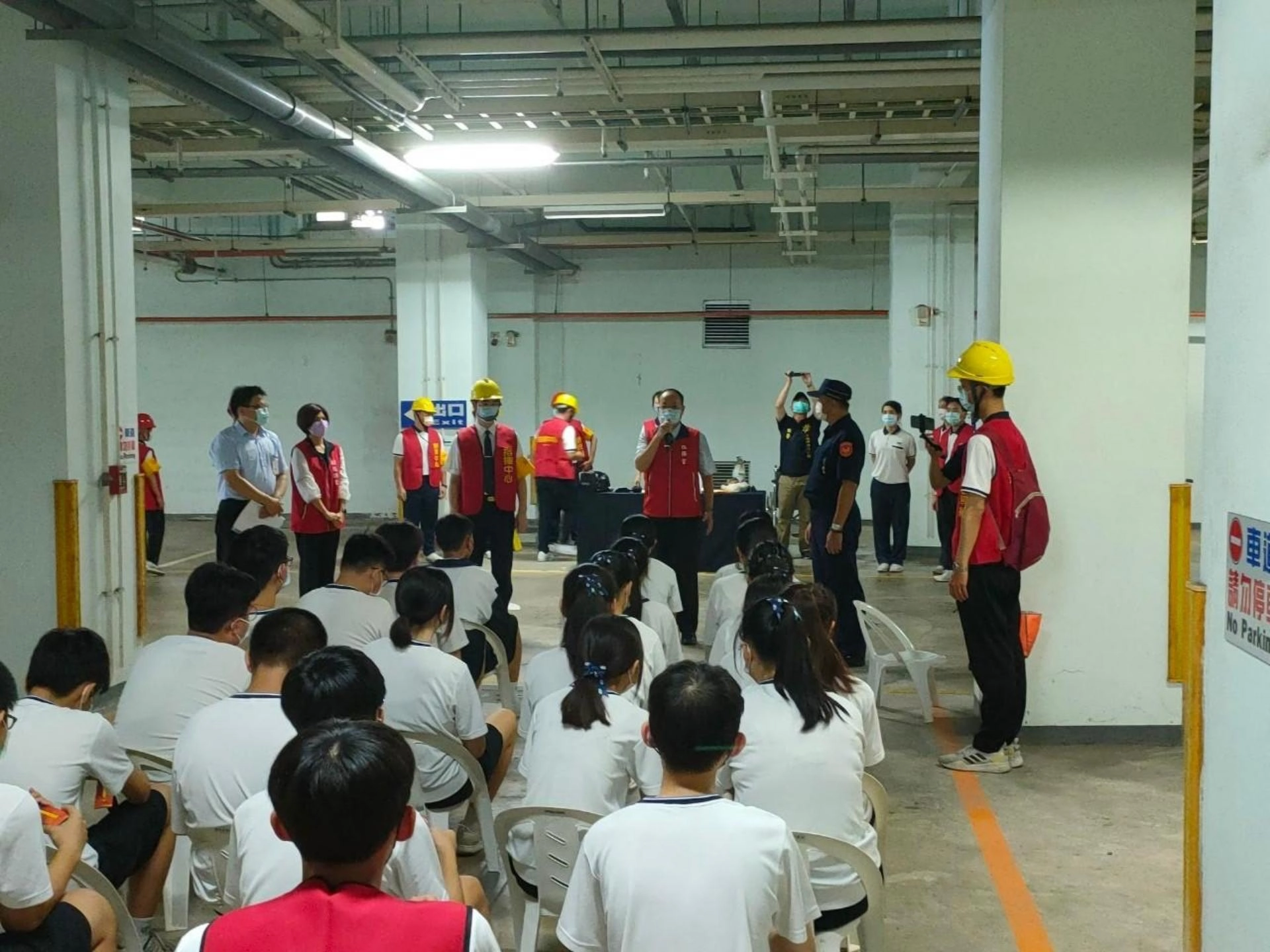 老師引導學生至地下停車場疏散避難區域,隨身攜帶班級防災避難包。