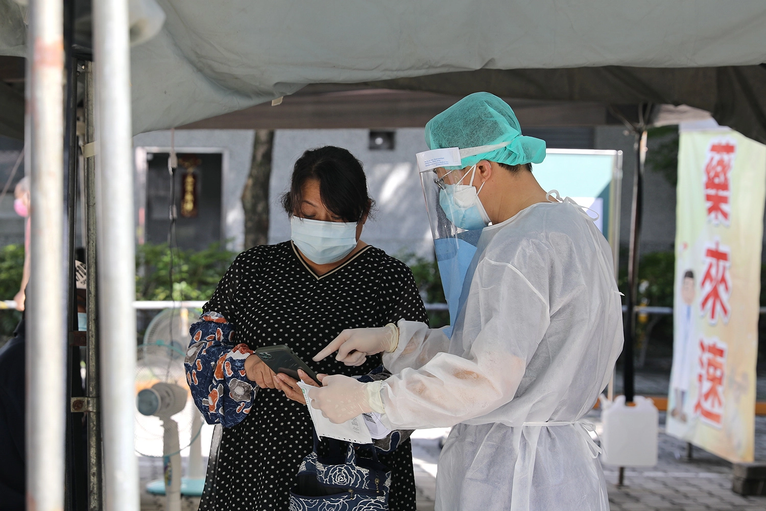 同仁身穿全身防護裝,協助民眾掃描藥袋上的QRcode,使用「醫指付APP」繳費。