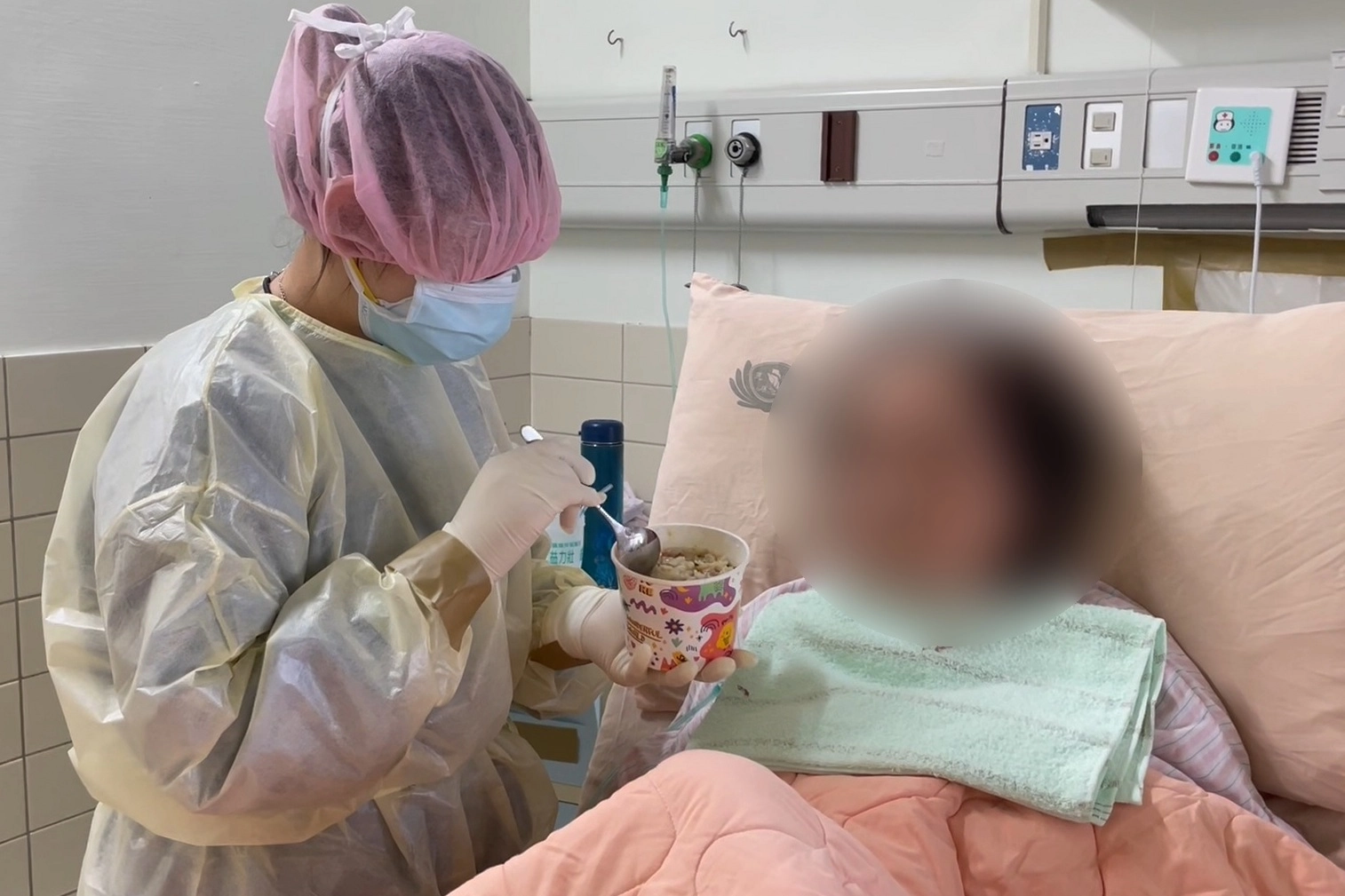 照護輔佐員協助護理師,做餵食、翻身、更衣、身體清潔等照顧工作,護理佐理員趙苡蘋(左)在專責病房裡餵確診者吃飯。