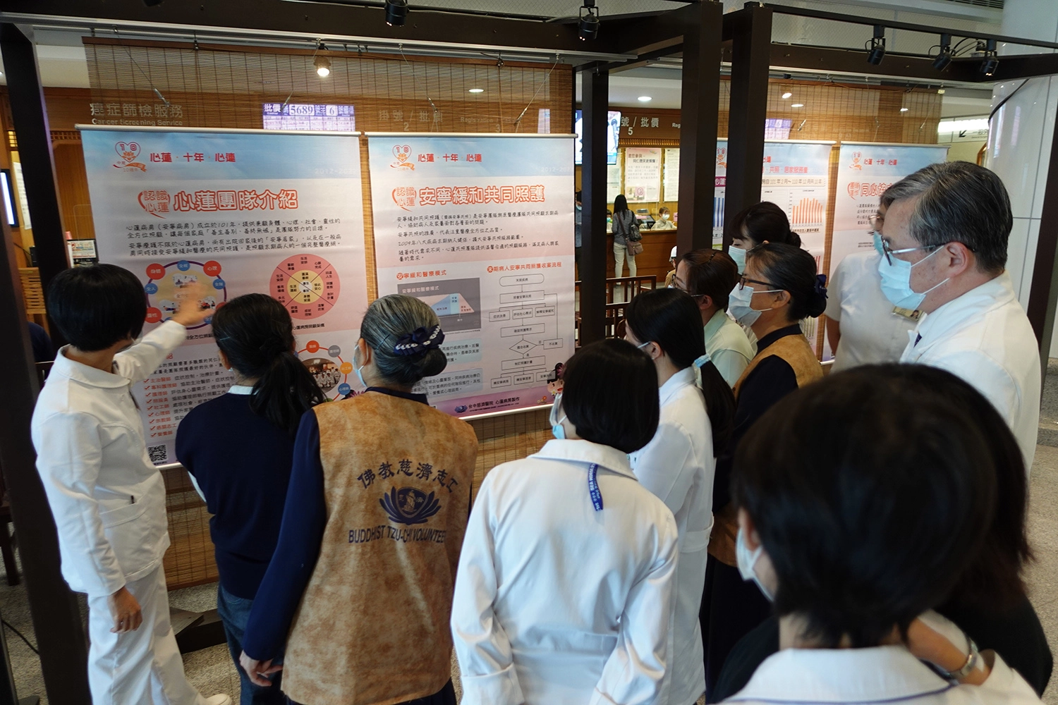 臺中慈院心蓮病房歡慶十周年 「成果海報展」揭序幕，黃美玲護理長為參觀的醫院同仁導覽。