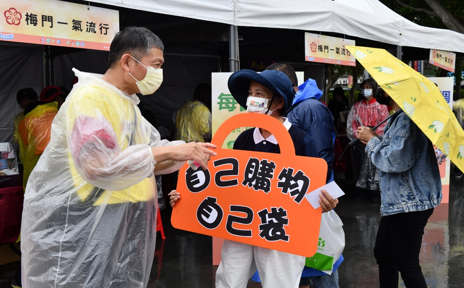 慈濟志工周秀琴手拿著「自己購物自己袋」的舉牌字樣,到每一攤位和各地照顧關懷據點的座位處進行宣導。