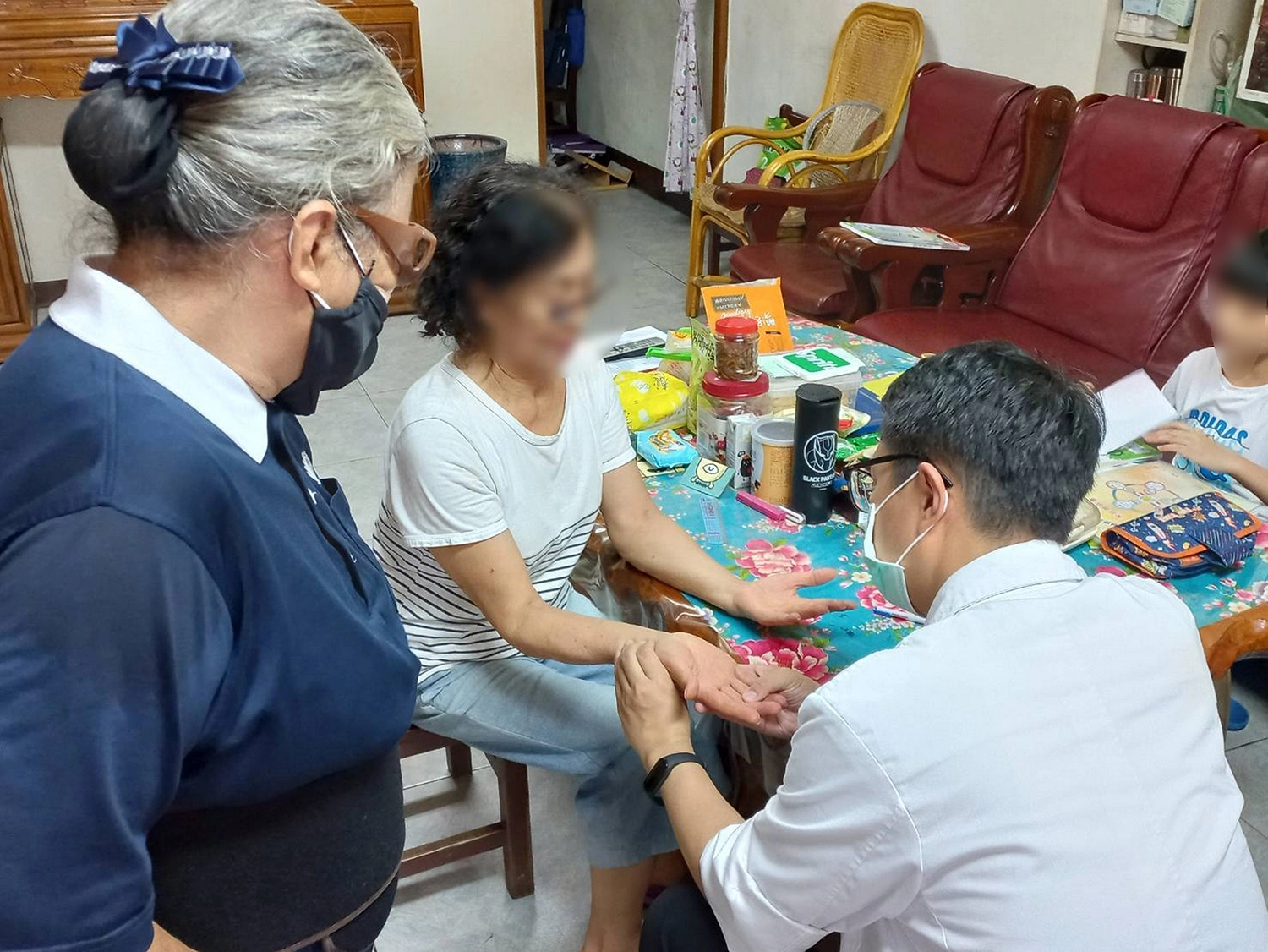 鄭主任透過望診察看手掌,瞭解往診鄉親身體狀況。