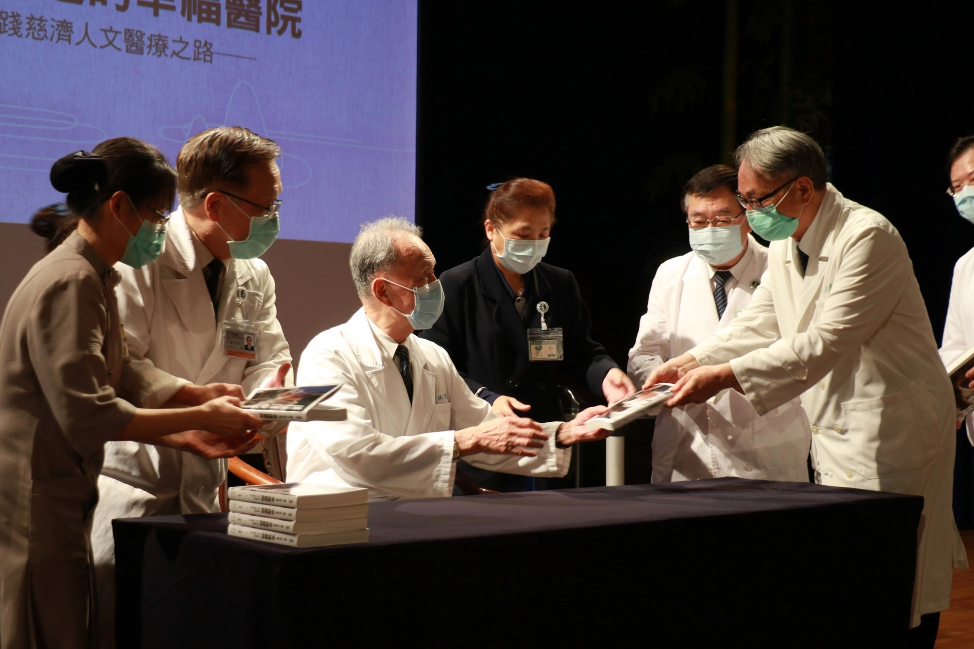王人澍(右)、蔡顯揚(右二)兩位臺中慈院副院長,從林俊龍執行長手中拿到有簽名章的新書。