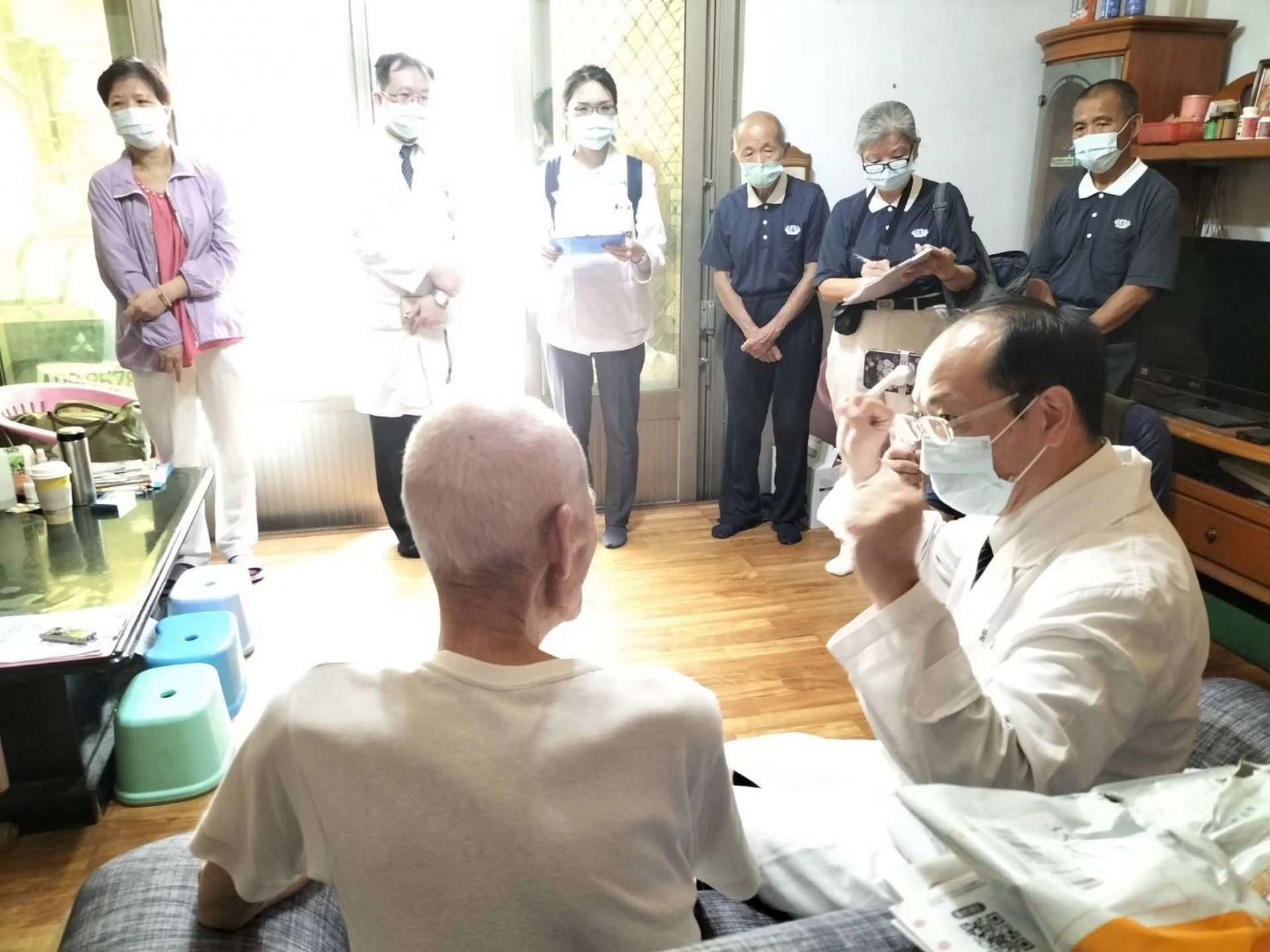 葉家舟主任(右)建議往診鄉親手拿裝滿水寶特瓶增肌。