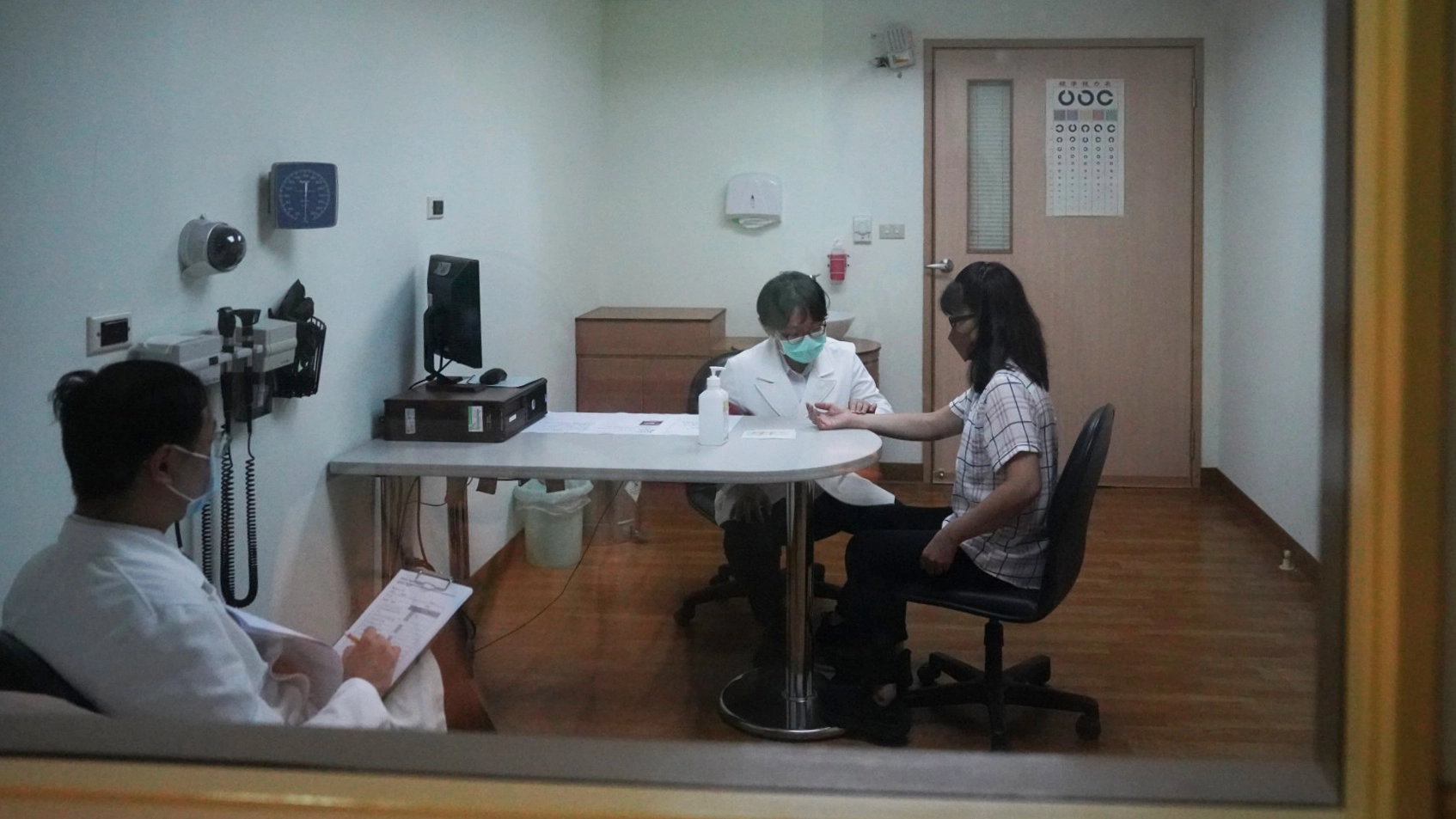 診間內,考生使用中醫忘、聞、聽、切四診與標準化病人看診,並詳細詢問病史,考官在一旁評分。