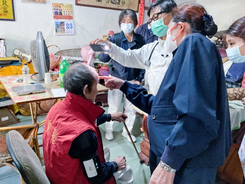 往診關懷上,林榮威醫師(法號:惟昶)以手機照明檢視阿公頭部傷口的癒合情形。
