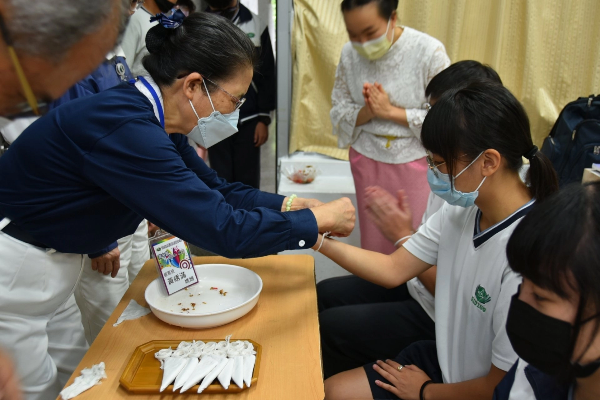 清邁慈濟學校老師引導學生為慈懿會爸爸媽媽雙手澆水並祝賀後,爸爸媽媽們也拍拍學生的頭和肩膀給予祝福,並綁上棉線、說吉祥話。