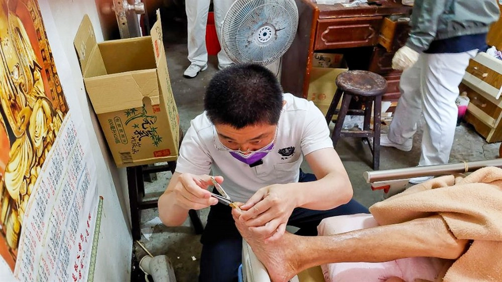 五月七日中區慈濟人醫會前往苗栗卓蘭山區展開往診關懷,曾景新醫師為阿公看診檢查後,再仔細地幫老人家修剪腳趾甲。