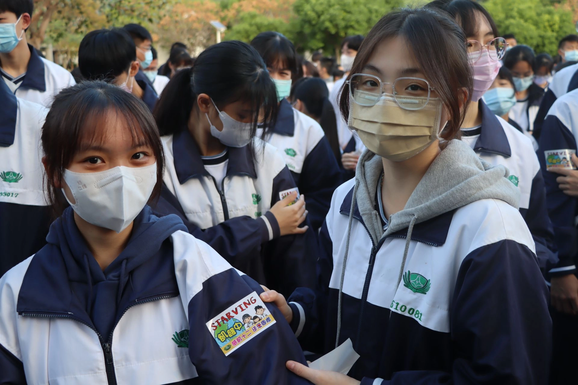 參與感飢活動的學生們為彼此貼上「飢餓中」貼紙,將自己省下的餐費捐助興建滿納海
